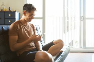 Man sitting on couch smiling down at his phone
