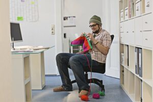 Smiling man knitting at work
