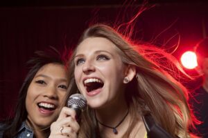 Two young women singing into a microphone together