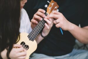 Close up of male instructor showing female student how to play ukulele