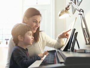 Woman showing young boy how to play piano