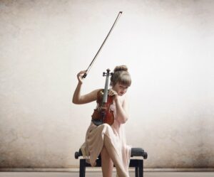 Little girl listening to violin while tuning