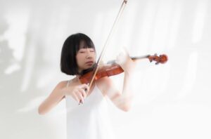Young woman playing the violin with her eyes closed