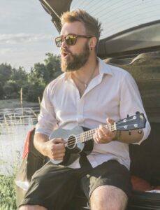 Bearded man singing and playing ukulele