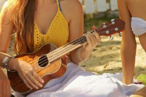 Young woman playing ukulele on a beach