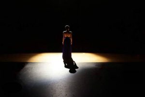 a stage actor stands in a spotlight