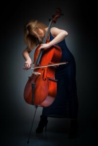 A woman in tall heels standing playing the cello