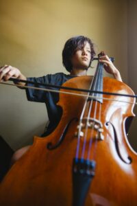 Little boy playing the cello with a serious facial expression