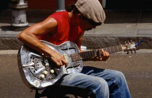 a young man playing a slide guitar song