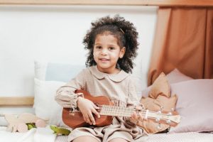 a little girl playing the ukulele