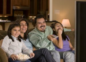 Smiling family eating popcorn and watching tv
