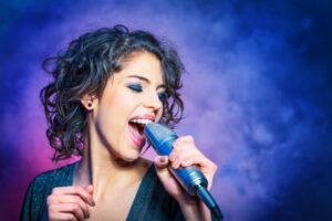 Woman with short hair singing into a microphone
