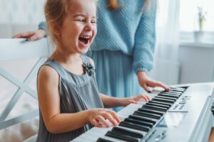 Young girl laughing and playing the piano