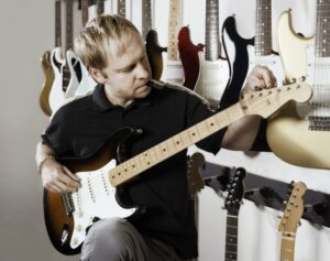 Blonde man tuning guitar