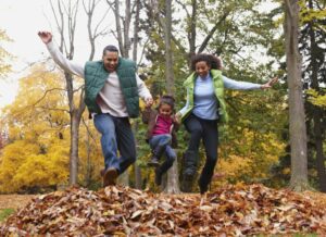 Family jumping into a pile of autumn leaves