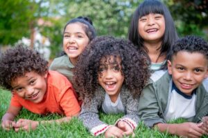 Group of kids laying in the grass outside smiling