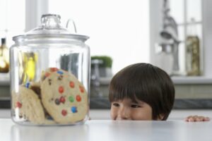 Little boy peeking over the counter to look at a cookie jar