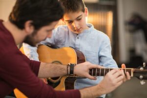 Man teaching boy how to play guitar