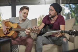 Man teaching teenager to tune guitar
