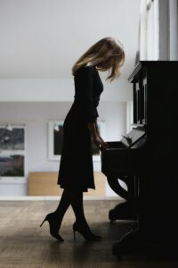 Woman in black dress standing at piano