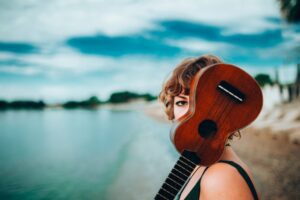 Woman on beach peeking from behind a ukulele