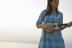 Young woman in a blue dress playing ukulele