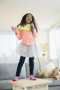 Curly haired girl standing on the table singing