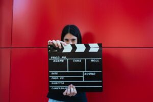 Girl holding a movie clapboard in front of a red background