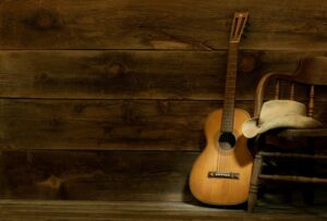 Guitar propped up against chair with cowboy hat