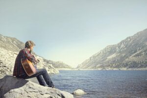 Man playing guitar by a lake