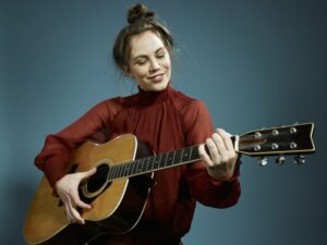 Woman in red shirt playing guitar
