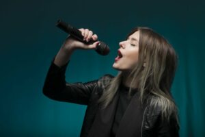 Woman singing into microphone with a blue background