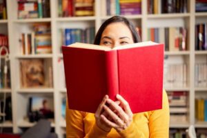 Woman smiling behind a red book