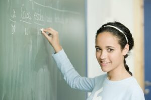 Teen girl answering a Spanish question on the board
