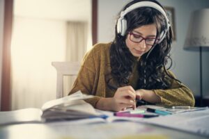 Teen girl studying while wearing headphones