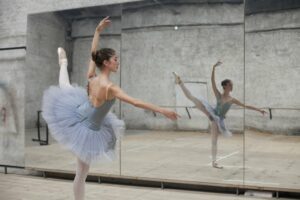 Ballerina in a blue mirror practicing in front of a mirror