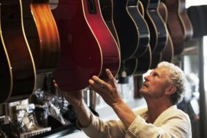 Older man looking at a guitar in a music store