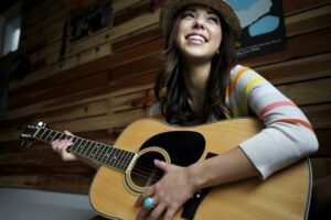 Young woman smiling playing an acoustic guitar