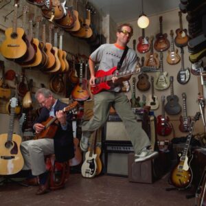 Two men playing with guitars in a music store