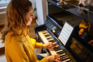 Young woman in a yellow sweater playing the piano