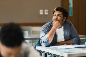 Teen boy looking out the window daydreaming in class
