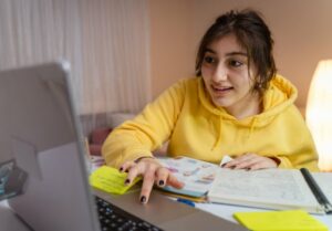 Teen in a yellow shirt smiling during virtual tutoring 