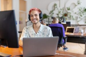 Pink haired man smiling in a business office
