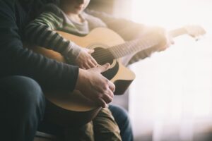 Close up of a father and son holding a used guitar