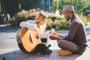 Man teaching a blonde student to play the guitar